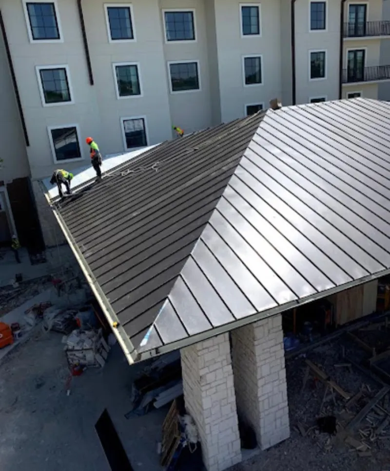 Crew installing standing seam metal roof panels on a commercial project in Hanover